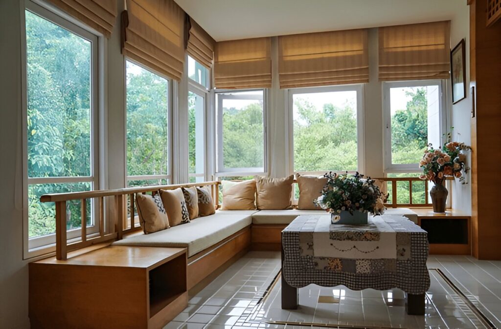 A warm and inviting wooden house interior featuring wooden-colored Roman blinds, a built-in bench with cushions, and a scenic outdoor view.