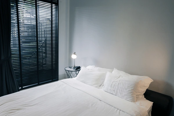 A modern bedroom with black window blinds, offering privacy, sunlight control, and eye strain reduction in a Dubai home.