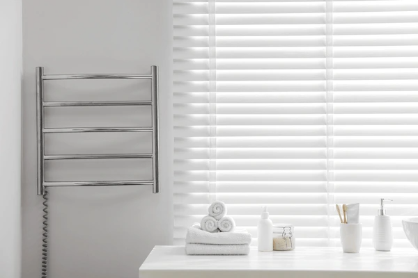 A stylish white bathroom featuring sleek white cut-size blinds, a heated towel rail, and neatly arranged towels and toiletries, creating a modern and luxurious ambiance in Dubai 2025.
