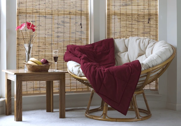Stylish bamboo window blinds in a modern Dubai home, enhancing sustainability with recyclable and eco-friendly materials. A cozy seating area with a papasan chair and wooden table completes the space.