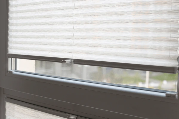 Close-up view of high-quality white honeycomb pleated blinds on a modern window, offering privacy and light control in Dubai 2025.