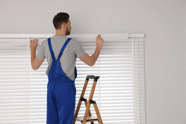 A professional installer from Emirati Blinds & Curtains fixing roller blinds in Dubai 2025.