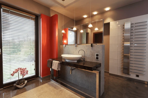 A high-end bathroom featuring a stylish vessel sink, a sleek black countertop, ambient pendant lighting, and large windows with contemporary white blinds.