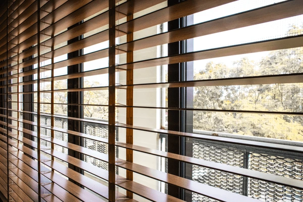 A close-up view of sleek wooden blinds covering large windows, offering a warm and stylish aesthetic with natural light filtering through, enhancing a modern home in Dubai 2025.