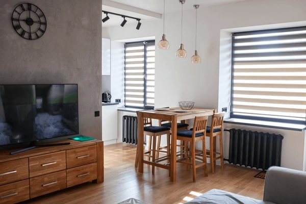 A stylish open-plan kitchen and dining area featuring zebra blinds on large windows, offering a sleek, modern look with adjustable light control for a perfect balance of privacy and illumination.