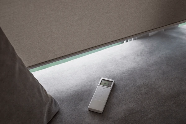 A modern motorized blind in Dubai with a remote control, designed for energy efficiency and cost savings.