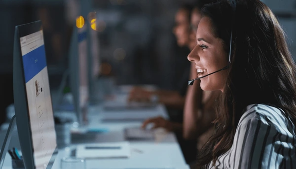 Friendly customer service agent from Emirati Blinds & Curtains assisting a client via headset in a modern support center.