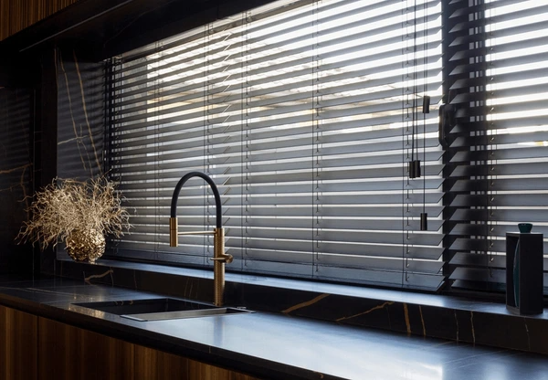 Sophisticated black wooden blinds in a luxury Dubai kitchen with gold accents and modern marble finishes.