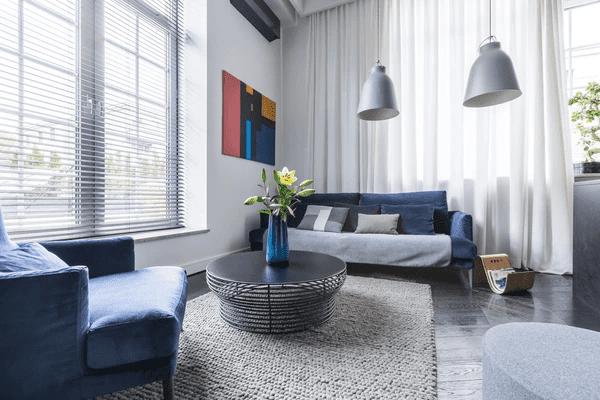 Elegant living room in Dubai 2025 with blue upholstered furniture, modern decor, and top-rated cozy blinds that enhance both luxury and comfort.