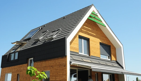 A contemporary wooden house with sleek exterior roller blinds and a retractable awning over large windows.