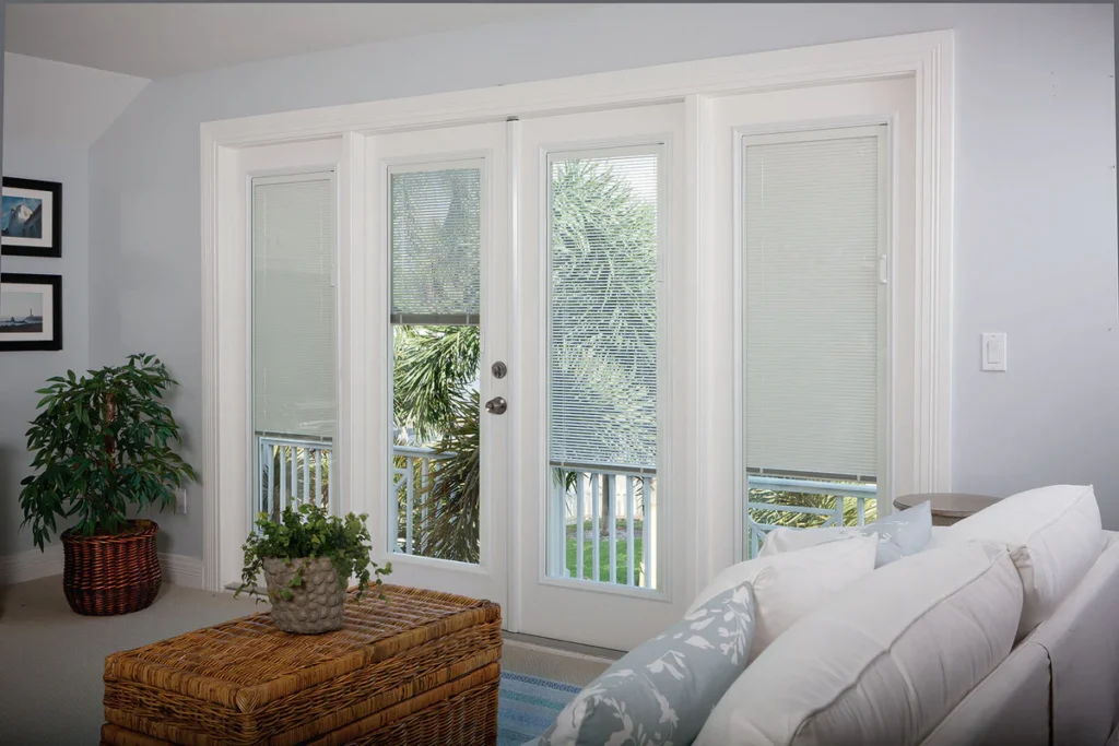 Elegant patio doors fitted with slim, built-in blinds, opening onto a lush green garden, surrounded by a cozy living room setup.