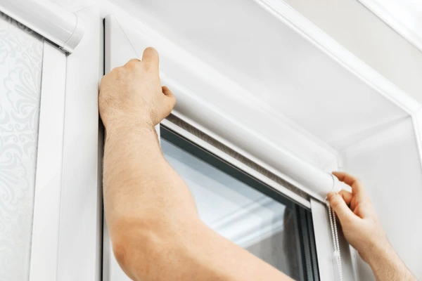 Professional hands carefully installing sleek white cord blinds on a modern window frame in Dubai 2025.