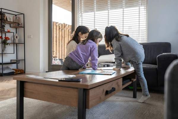 Mother and two children playing near a large window with sleek, modern fire resistant blinds in a cozy Dubai living room.