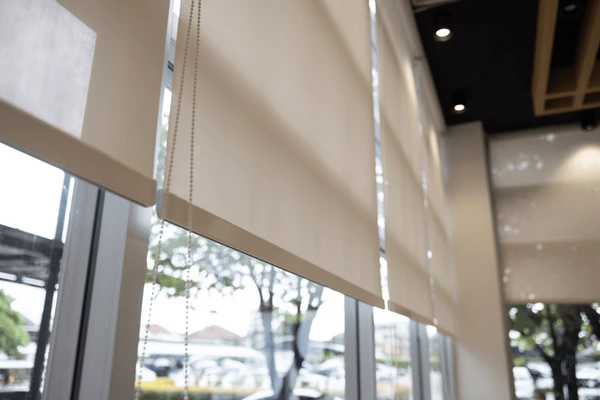 Close-up view of sleek, white fire resistant blinds on large glass windows in a contemporary Dubai interior.