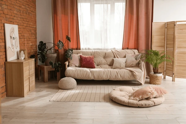 Modern cozy living room with beige sofa, indoor plants, and elegant red and white layered curtains filtering soft daylight.