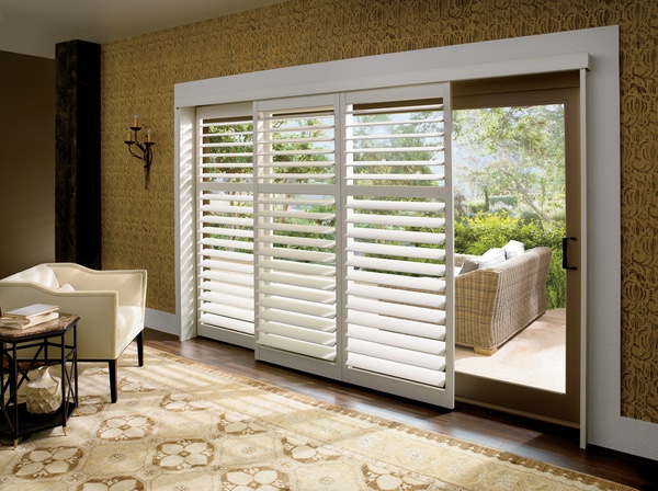 White sliding door plantation shutters installed on a patio entrance, adding elegance to a modern living room.