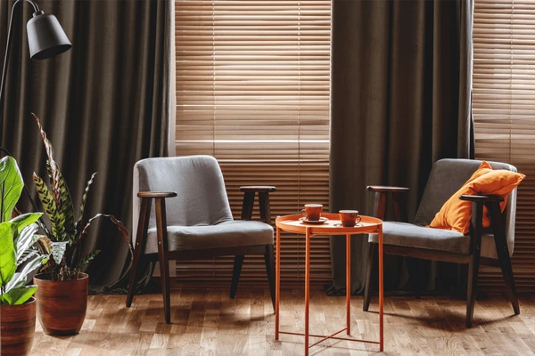 Stylish living room with wooden recycled blinds, vintage armchairs, and earthy tones showcasing sustainable and elegant décor perfect for cozy Dubai homes in 2025.