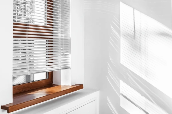 Best Short Blinds in Dubai 2025 - Close-up of white venetian blinds covering a small window, blending luxury with modern design.
