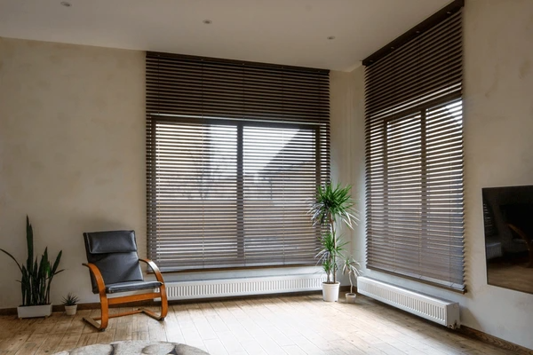 Spacious living room in Dubai featuring large windows with motorized wooden blinds and indoor plants for a natural, elegant touch.