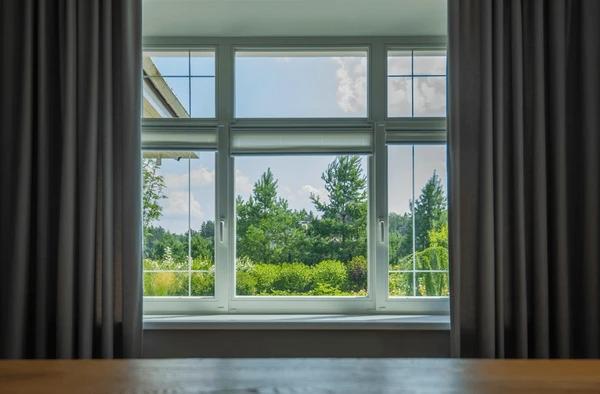 Large window with scenic outdoor view framed by blackout curtains and hidden anti-condensation blinds in a Dubai home.