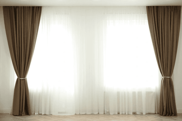 Floor-length taupe curtains paired with sheer white inner panels, designed for insulation and modern aesthetics.