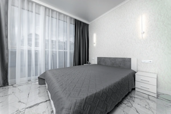 Best Drop Curtains in Dubai 2025 - Elegant gray and white drop curtains complementing a modern bedroom with sleek furniture and marble floors.