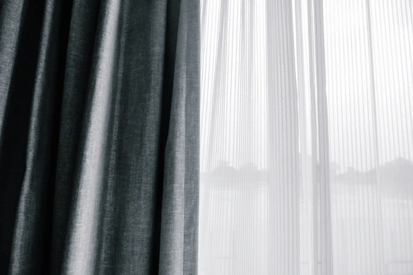 Elegant double-layered curtains featuring a dark outer drape and sheer white inner layer, filtering soft daylight.