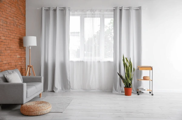 Bright and airy living room with stylish sheer curtains, modern gray sofa, and indoor plants – showcasing luxurious sheer curtain trends in Dubai 2025