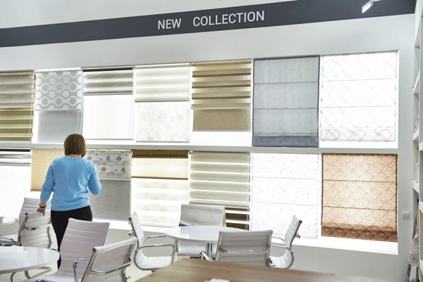 A woman exploring a wide showroom display of various stylish blinds in Dubai’s top-rated 2025 home decor collection.