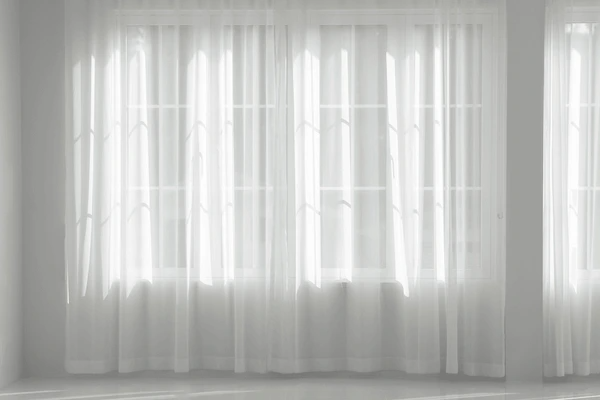 A minimalistic and elegant window with thin, white, shrink-proof curtains letting in soft natural light, perfect for modern Dubai homes in 2025.