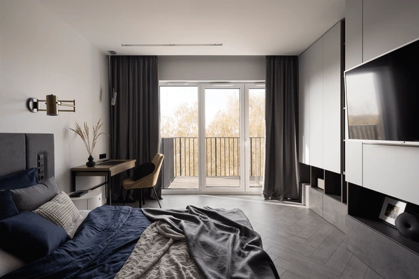 A spacious and modern bedroom with dark shrink-proof curtains that offer a sleek, sophisticated design, enhancing the room's luxurious atmosphere.