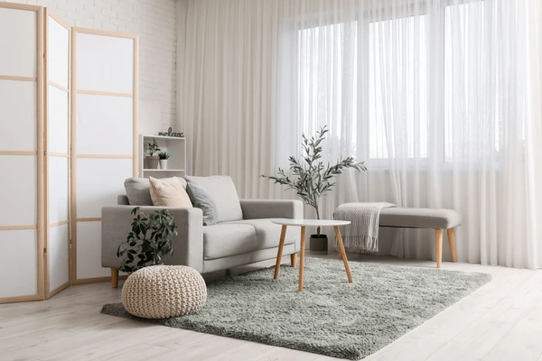 Stylish Scandinavian-inspired living room with elegant unwrinkled white curtains, soft grey furniture, and minimal décor.