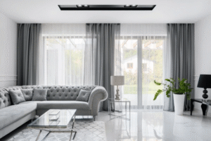 Contemporary living room with sleek grey used curtains, covering large modern glass windows paired with a tufted grey sofa and marble floor.
