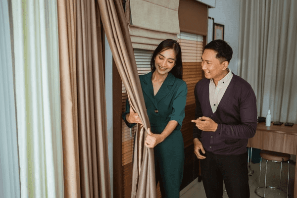Smiling woman exploring curtain fabric with a consultant in a Dubai showroom, reflecting satisfied customer experience in curtain shopping.