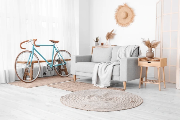 Light-filled modern living room with sheer white curtains, a grey sofa, and a vintage blue bicycle as decor.