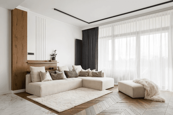 Modern Dubai living room with sleek black blackout curtains paired with white sheer panels, complementing a beige sectional and minimalist decor.

