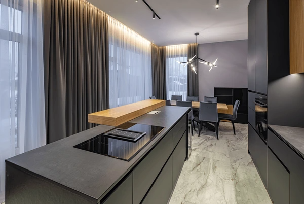 Dubai modern kitchen with full-length brown and white layered curtains, marble flooring, and matte black cabinetry.