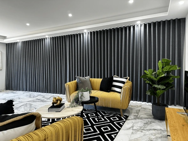 Modern Dubai living room with yellow velvet sofas, black blockout curtains, and a marble floor perfect for cozy winter interiors.