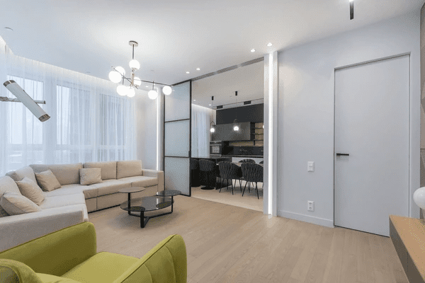 Modern Dubai studio apartment with sheer white curtains over sliding glass windows, adding softness, light diffusion, and elegance to the open living area.

