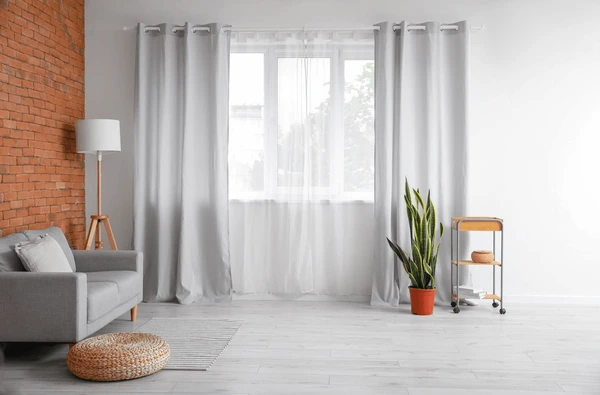 Modern living room in Dubai with grey wall-to-wall curtains and sheer inner layers, creating a clean and stylish look.