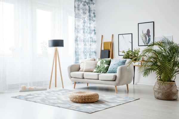 Bright living room with patterned blue sheer curtains, modern sofa, indoor plants, and natural cozy Dubai home design 2025.
