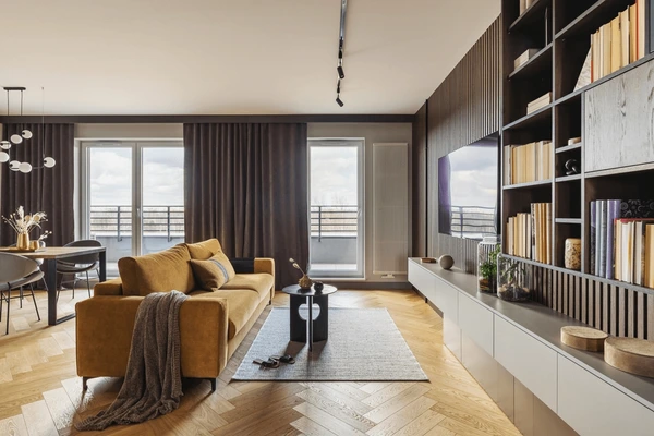Luxurious dark modern curtains in a stylish Dubai living room with mustard sofa, wooden flooring, and sleek shelving, perfect for 2025 home trends.