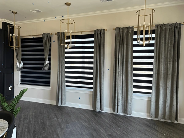 Elegant living room with grey velvet curtains and black-striped zebra blinds, blending luxury and functionality in a stylish Dubai home interior.