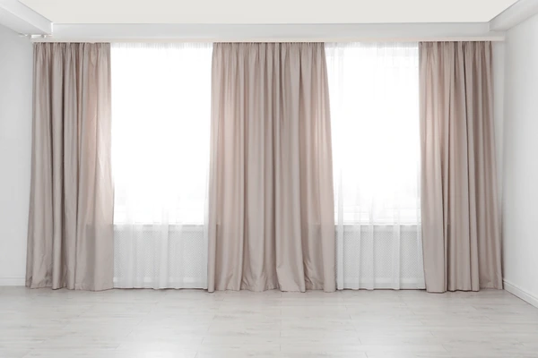 Elegant beige easy-to-dry curtains in a bright modern Dubai home interior with large windows and minimal decor.