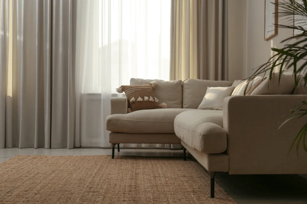 Elegant beige washable curtains behind a modern sofa in a sunlit Dubai living room, representing the best washable curtains in Dubai 2025 for stylish and practical homes.