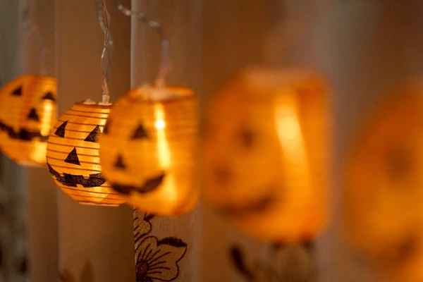 Close-up of glowing pumpkin lanterns hanging on Halloween curtains in a Dubai home, creating a cozy festive ambiance.