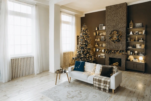 A modern living room in Dubai decorated for the holiday season, featuring tall white sheer curtains, a Christmas tree, and warm lighting that creates a cozy, elegant November ambiance.
