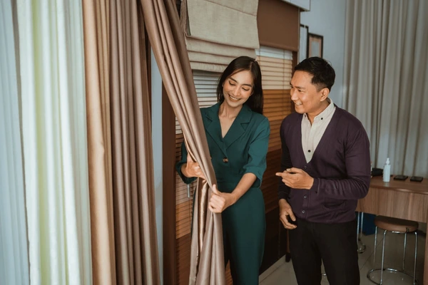 Two people examining premium blackout curtains inside a modern showroom best blackout curtains shop in Dubai 2025 Emirati Blinds and Curtains