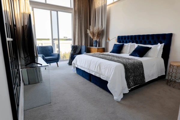 Elegant bedroom with a plush blue bed soft lighting and tall beige blackout curtains blocking sunlight best blackout curtains for Christmas in Dubai 2025